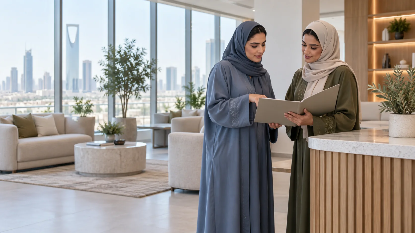 منسقتان بعباءتين زرقاء وزيتونية تراجعان ملفاً مفتوحاً بجانب طاولة استقبال في بهو مكتب