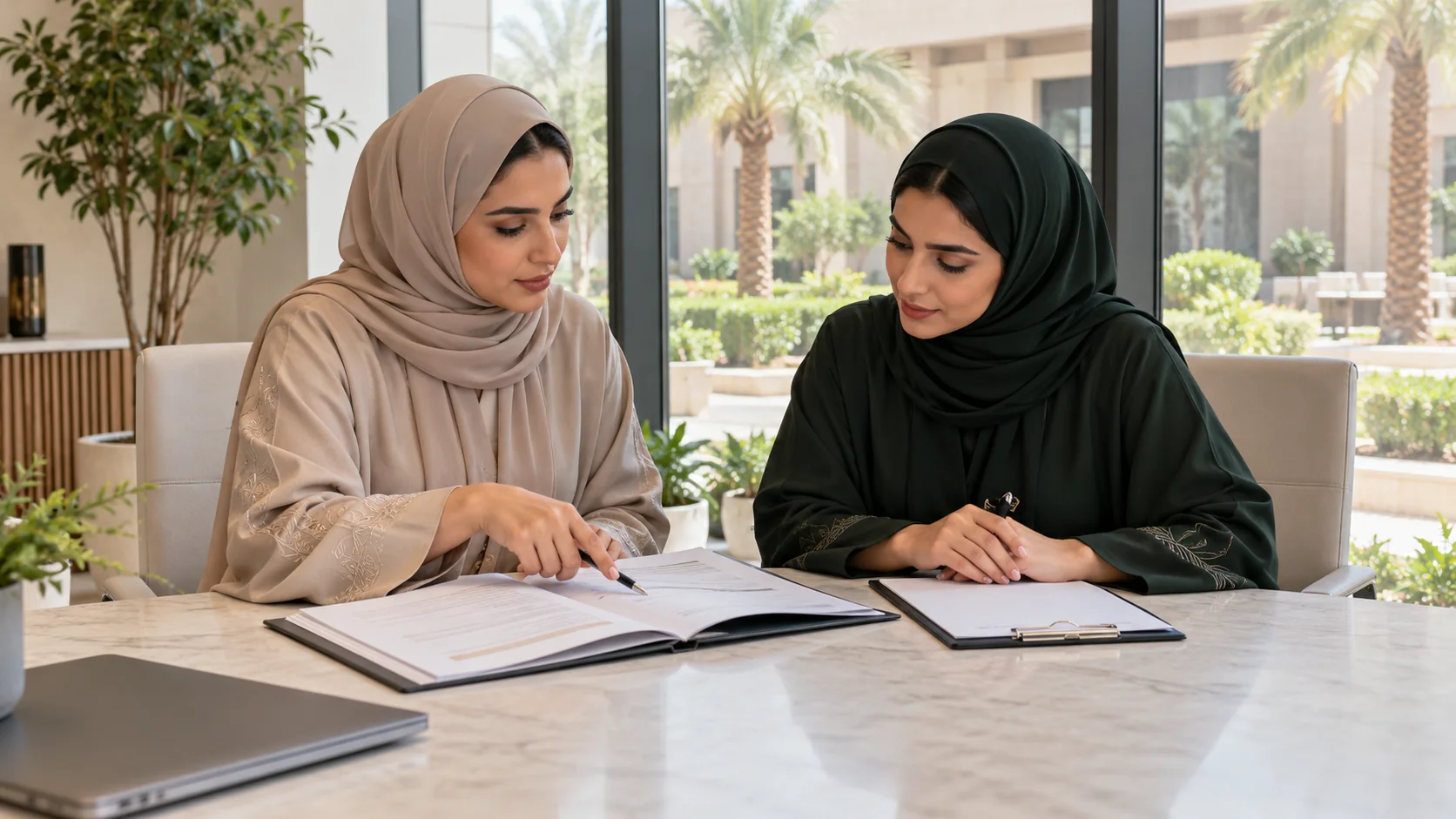 مشهد توضيحي لمنسقتين ترتديان عباءتين رملية وخضراء تراجعان ملف متطلبات العمل على طاولة اجتماع